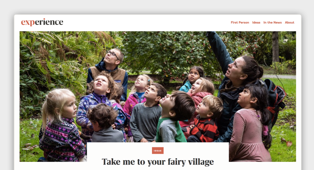 The Experience Magazine website with a large photo of schoolchildren learning from a pointing teacher outside, with navigation above and the headline "Take me to your fairy village" below