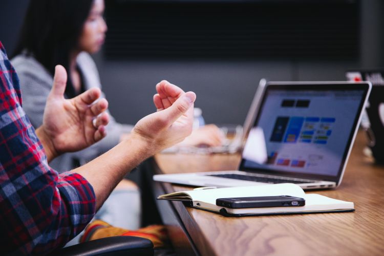 People gesturing in front of a computer in a meeting that matters