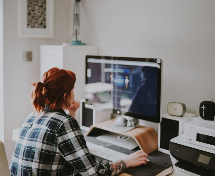 Woman working in a home office, using an iMac