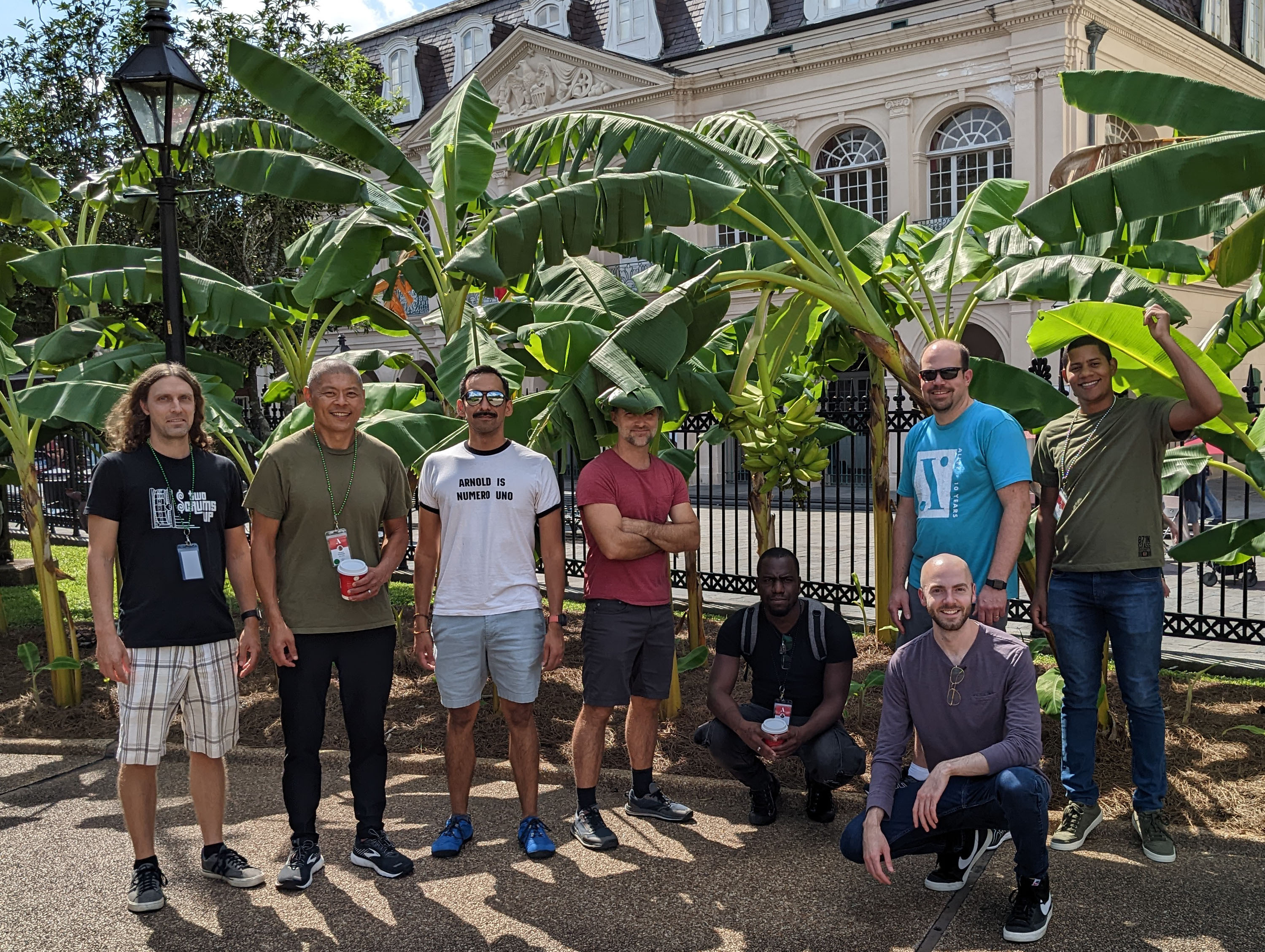 A group of eight Alley developers hanging out in the shade of banana trees